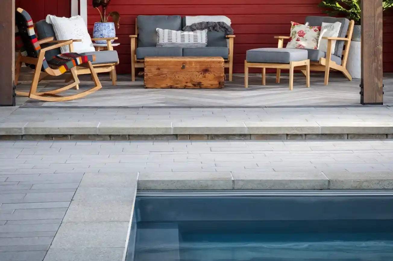 Laguna Coping Product Photo2 Laguna Coping installed on the edge of a pool with a seating area in the background.