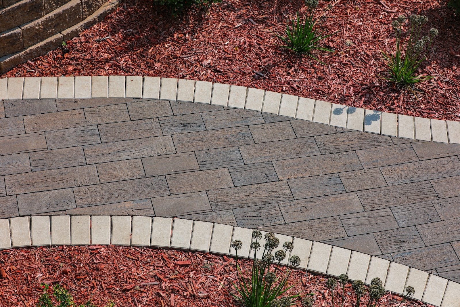 Walkway installed with Essence Plank Pavers with red mulch.