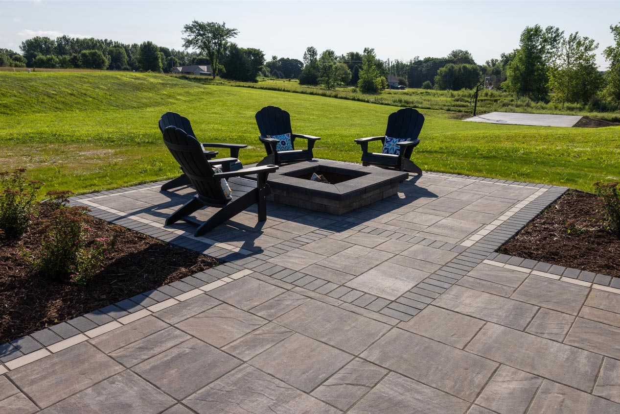 Water front patio made with Tranquility Paver Set with a firepit and seating looking out onto the water.