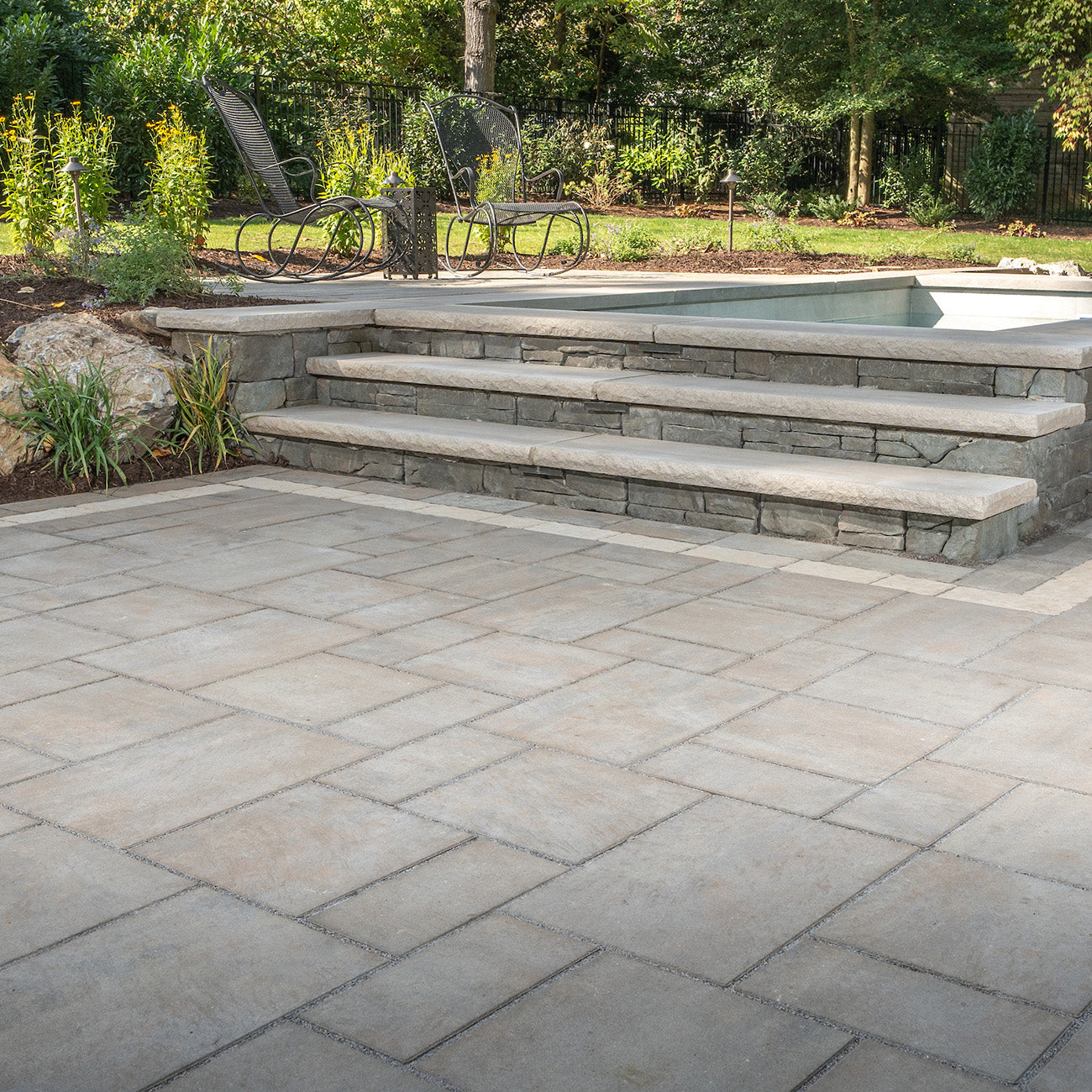 Luxury Patio & stairs to a raised pool area installed with Trilogy+ Smooth Pavers.