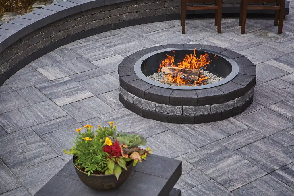Summit round fire pit in colours Majestic and Reflection. Circle patio with Grand Discover pavers in Majestic. Summit retaining wall in colour Reflection.