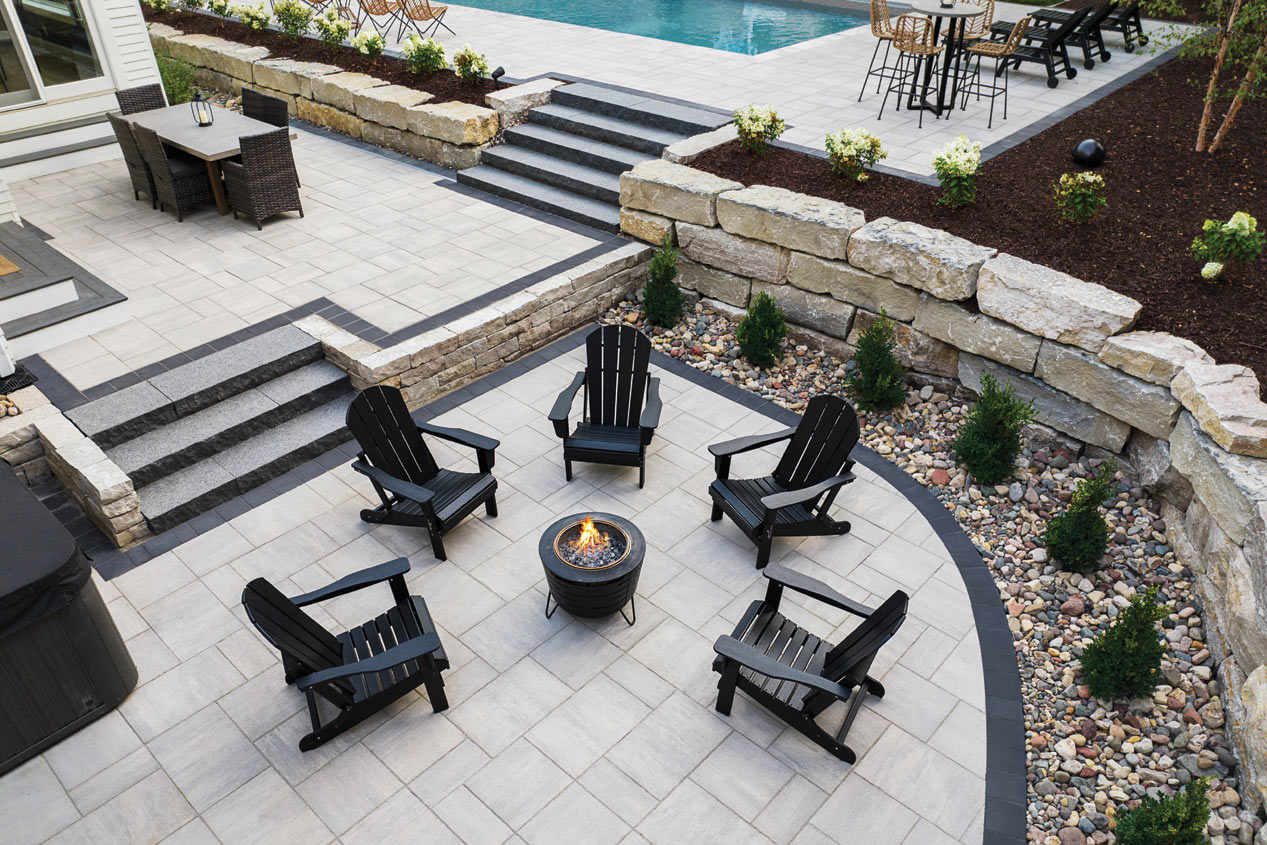 Luxury patio with a firepit area and a pool deck. Using Grand Discover pavers in Allure.
