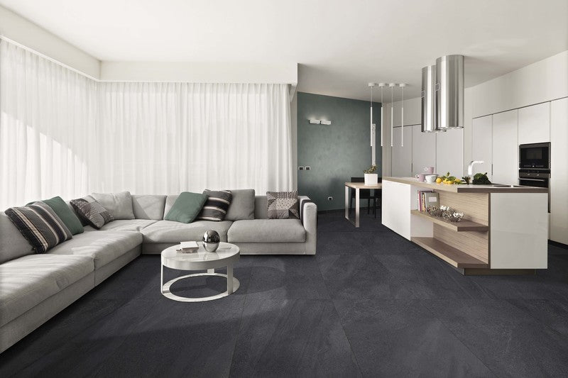 Modern open concept living room and kitchen with dark tiles installed on the floor