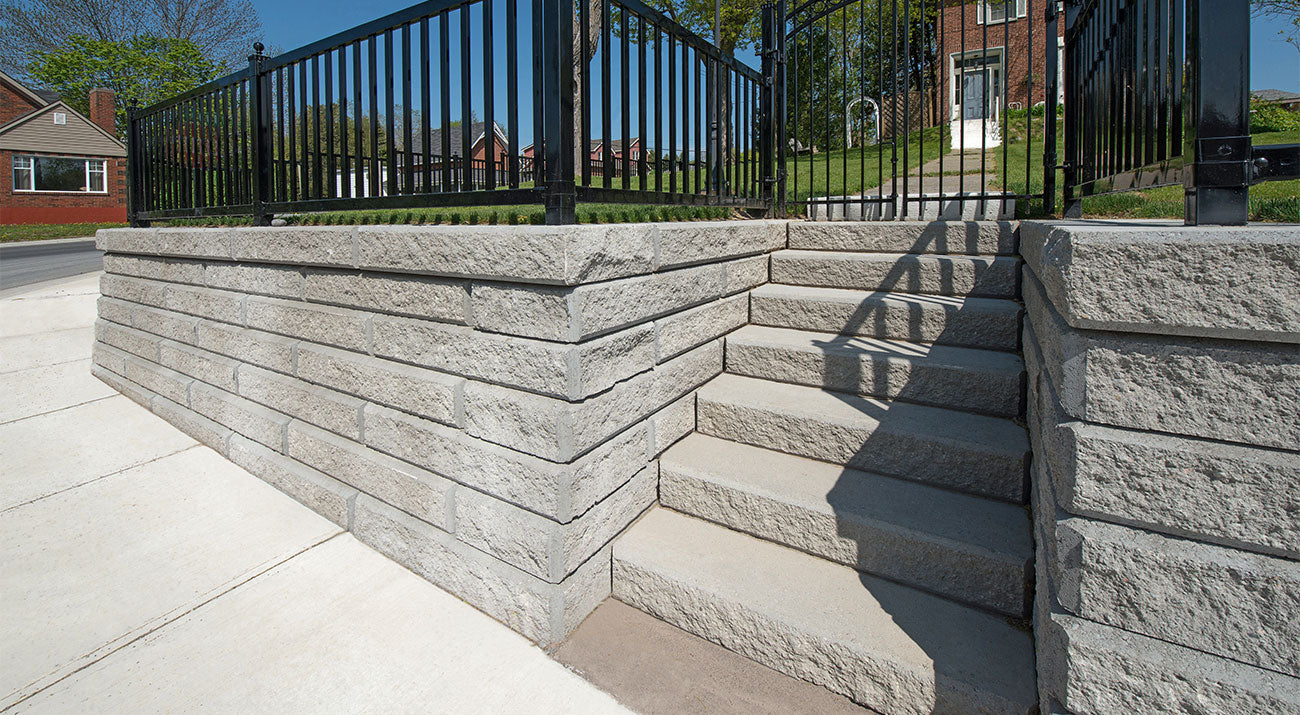 Retaining wall system made with Windsor Wall Blocks retaining a flower bed with pink and red flowers.