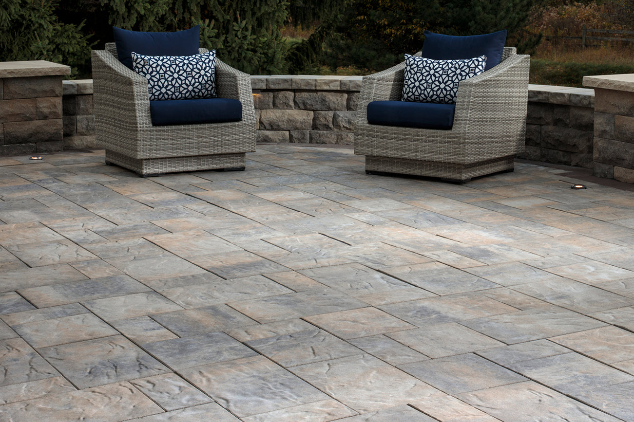 Patio made with large Origin Paver Set with a retaining wall and pavers, with 2 patio chairs.