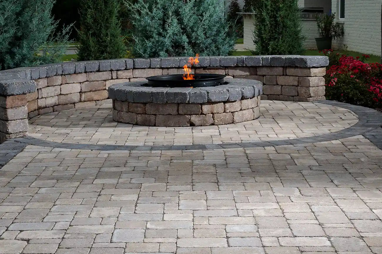 Circular patio made with Mega-Dublin Pavers with a fire pit in the middle and a retaining wall around it.