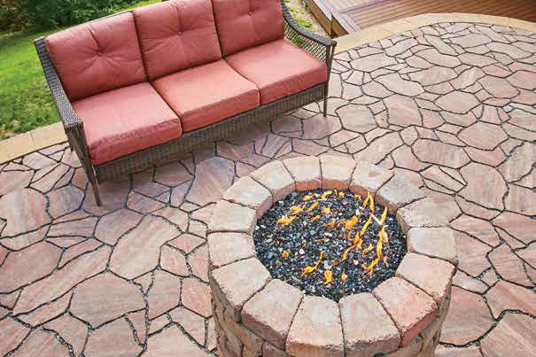 Fire pit on a patio made with destination pavers with a red couch