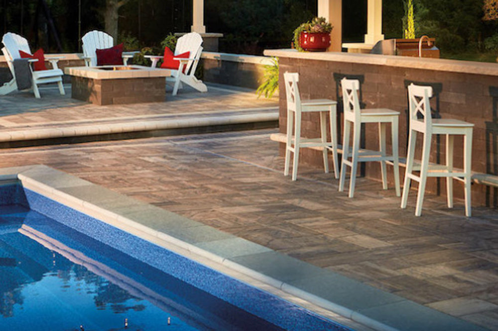 Pool side patio with a bar and fire place Made with Grand Tranquility Pavers
