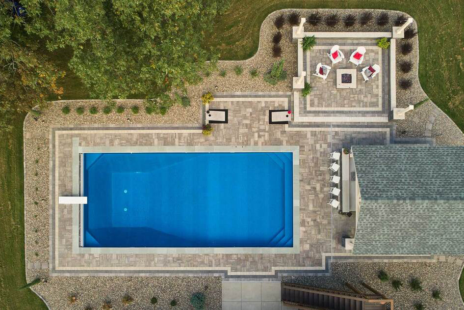 Birds eye view of a pool and poolside patio with a fire place.