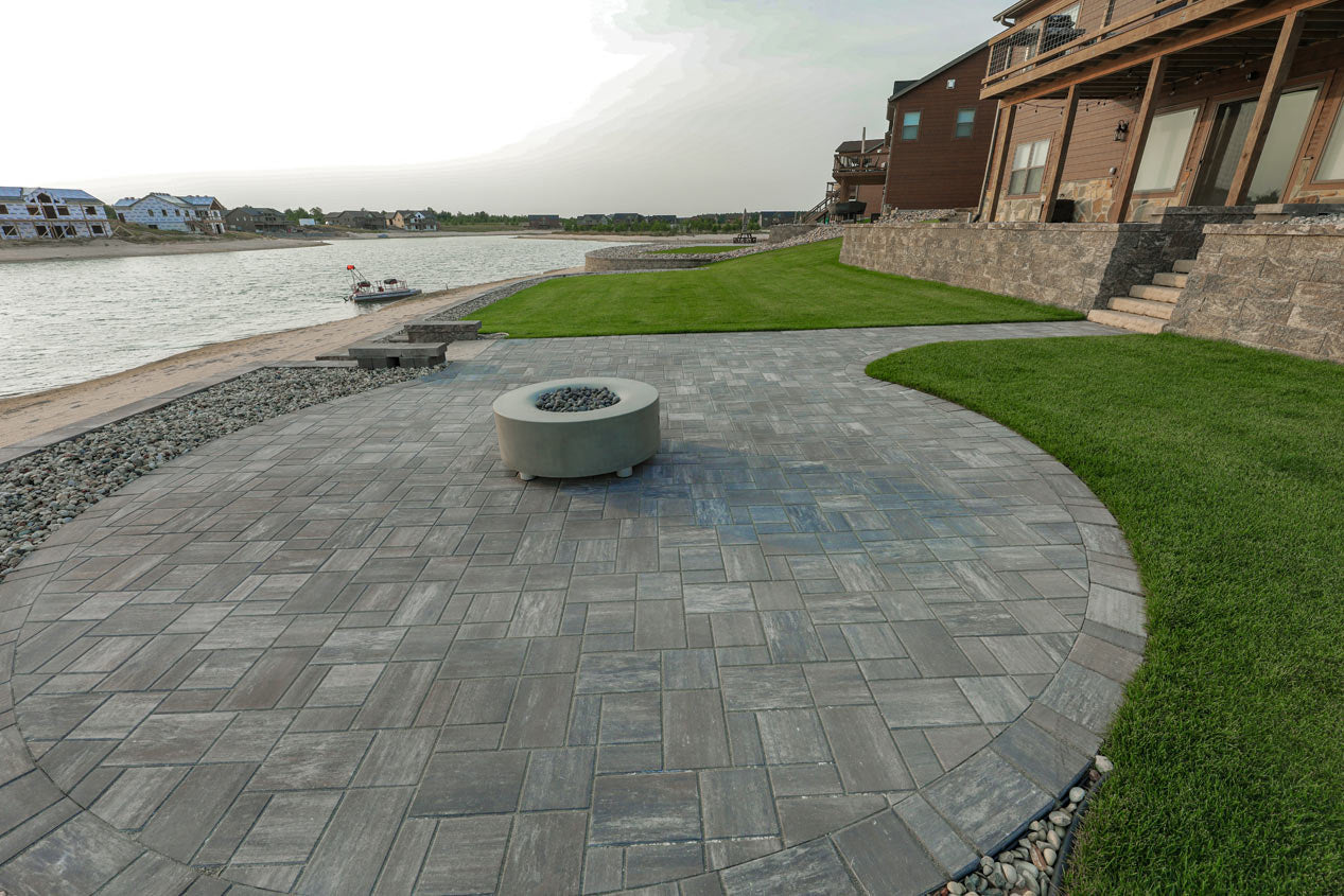 circular patio with a fire pit, walk way up to a house and a pond.