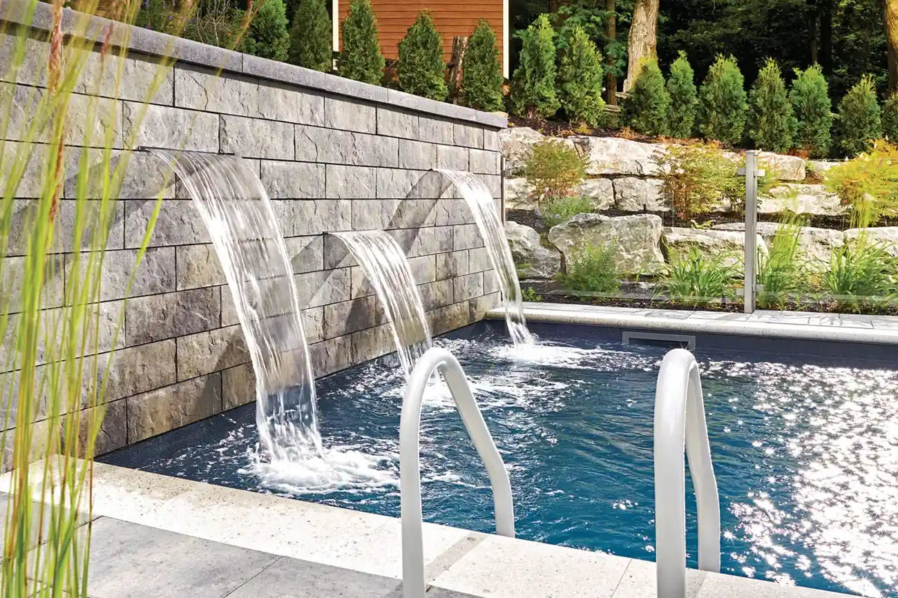 Water feature wall with three fountains going into a swimming pool.