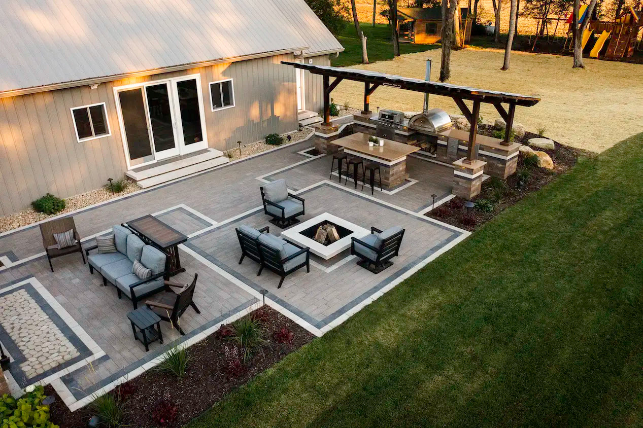 Summit Square Fire Pit on a patio with an outdoor kitchen and seating area on a water front property