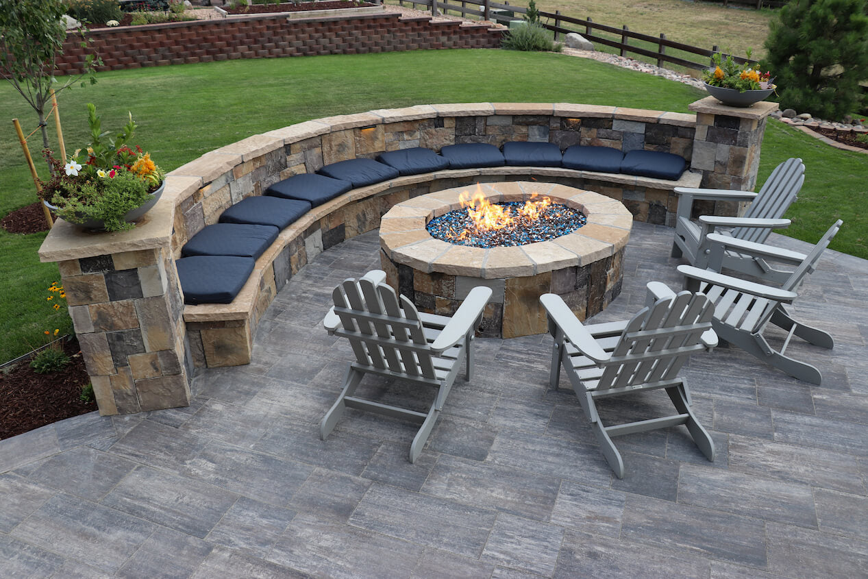 Patio made with Grand Milestone Paver Set with a fire pit area and a retaining wall with bench.