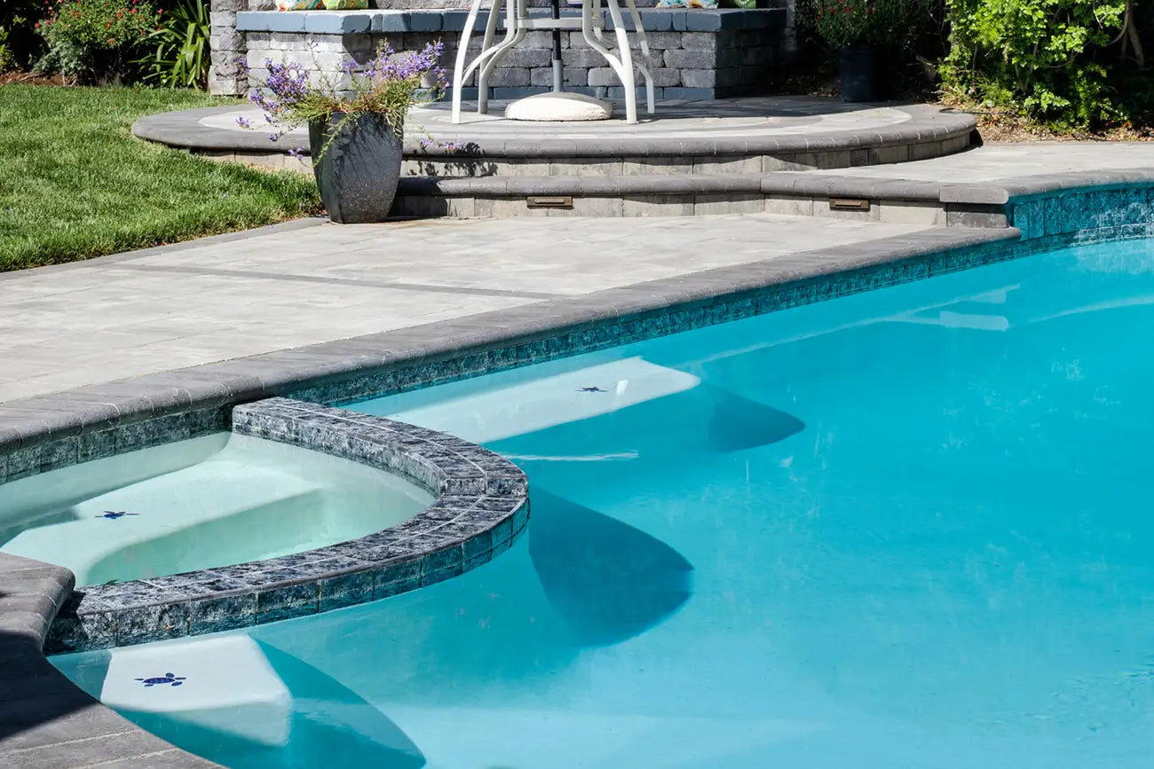 Pool with a hot tub with marina coping installed around the edge of the pool