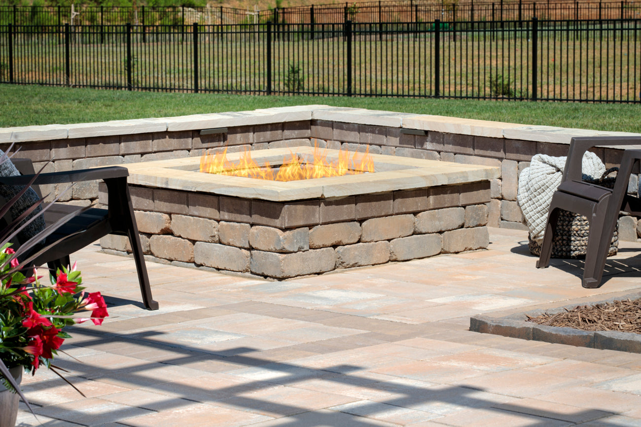 Weston Square Fire Pit on a patio with a retaining wall and chairs
