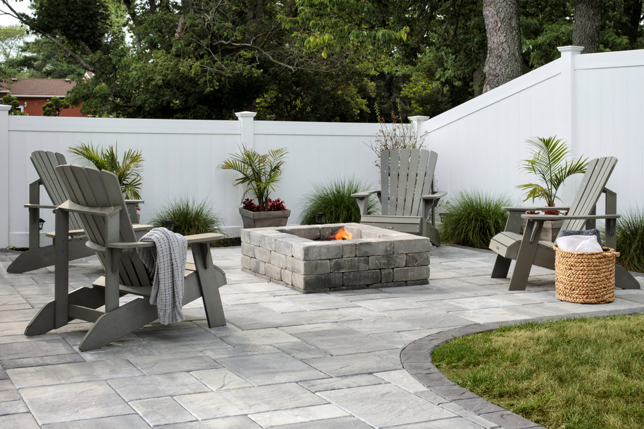 Weston Square Fire Pit on a patio with a seating area surrounded by a white fence.